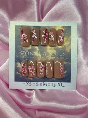 Sakura (M);Medium Square;Curved - Handgjorda press-on naglar i glittrig nude med sakura blommor i rosa, vitt och grönt. Naglarna har en elegant, medium längd och square form med glansig finish. Perfekt för dig som vill ha en unik och kreativ nageldesign.M: 16 mm, 12 mm, 12,5 mm, 11,5 mm, 10 mm