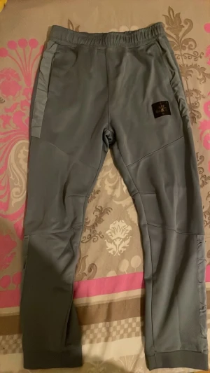 Grå Nike Air Max mjukisbyxor - Snygga grå mjukisbyxor från Nike Air Max med elastisk midja och muddar vid bensluten. Byxorna har fickor på sidorna och logga på låret samt Air Max-tryck på baksidan. Perfekta för chill eller träning, tillverkade i mjukt material.