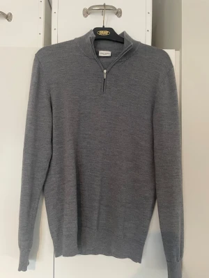 Grå Halfzip John Henric - Snygg grå stickad tröja från John Henric med halv dragkedja och hög krage. Tillverkad i mjukt material, perfekt för lager på lager. Långa ärmar och ribbade muddar ger en clean look.                       Vid intresse kontakta för fler bilder!                            Tveka inte på att fråga något!