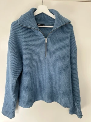 Blå stickad tröja med halv dragkedja - Mysig blå stickad tröja från Bik Bok med ribbad struktur och halv dragkedja framtill. Tröjan har hög krage och långa ärmar, perfekt för kyliga dagar. Passformen är avslappnad och materialet känns mjukt mot huden. Nypris ca 600 kr💕