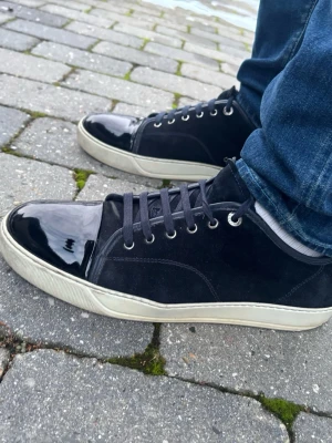 Lanvin Cap Toe - Marinblå (Box ingår!) - Exklusiva Lanvin dbb1 i mörkblå mocka. Sjukt snygga sneakers! 🧵 Märke & Modell: Lanvin - Cap Toe 📏 Storlek: Uk11 strl 45/46 🧩 Material: Premium mocka & lackskinn ✅ Skick: 7/10 - Fint skick överlag. Liten spricka i sulan vid hälen på båda. Jag har haft skorna 1 år och fick dem så. Jag har använt dem en del och det har inte märkts något alls. Det är även några små revor i lacken (normalt slitage). Det märks eller stör ej vid användning. Originalbox från Lanvin ingår vid köpet! ‼️ Skickas inom 24h ‼️