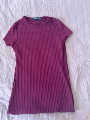 Ribbad vinröd kortklänning Boohoo - Kort ribbad klänning från Boohoo i en snygg vinröd färg. Klänningen har rund halsringning och korta ärmar, perfekt för en avslappnad men trendig look. Materialet är stretchigt och bekvämt.