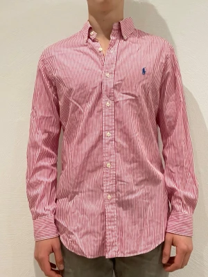 Rosa/vit randig skjorta från Ralph Lauren - Ralph Lauren skjorta || Storlek M (slim fit) || Skjortan är i bra skick || Modellen på bilden är 170cm och väger 62kg || Tveka inte på att höra av dig vid frågor eller funderingar 