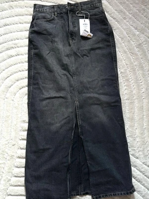 Svart lång jeanskjol från ONLY - Snygg svart lång jeanskjol från ONLY i tvättad denim. Kjolen har slits framtill. Helt ny oanvänd