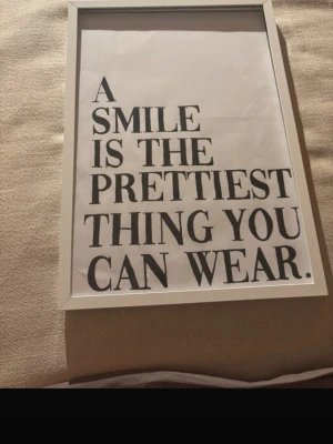 Poster med citat - Snygg tavla med citatet 'A smile is the prettiest thing you can wear.' Tryckt i svart text på vitt papper och inramad i en enkel vit ram. Perfekt som dekoration till sovrum, vardagsrum eller hall. Säljes utan tavelramen💗