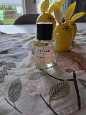Aurora Vanille parfym från Essnce - Aurora Vanille Eau de Parfum från Essnce. Flaskan är genomskinlig med svart lock och har en enkel, stilren etikett i vitt med svart text. Doften har inslag av vanilj och parfymen är tillverkad i Frankrike.