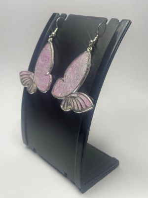 Lila fjärilsörhängen  - Unika örhängen formade som fjärilar i lila och silver. De är gjorda i resin med glittrig finish och har metallkanter. Perfekta för dig som vill ha något lekfullt och färgglatt i din stil.