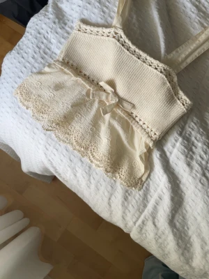Krämvit topp från Zara - Supersöt krämvit linnetopp från Zara med virkade detaljer upptill och spetskantad volang nertill. I storlek S