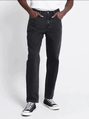 Svarta jeansbyxor från 157 - Säljer ett par svarta jeansbyxor från 157 med klassisk femficksdesign och dragkedja. Byxorna har normal passform och raka ben, perfekta för en stilren vardagslook. Midjemått W34 och längd 34. Inga hål eller slitage alls bara att stryka och använda  Bredd ca 44 cm Benlängd ca 75 cm