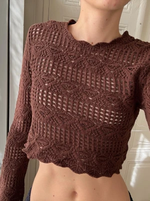 Brun virkad croptröja  - Säljer en brun långärmad croptröja med virkat mönster och vågig nederkant. 