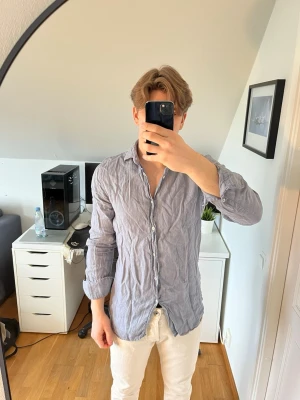 Ljusgrå linneskjorta från Massimo dutti - Säljer en ljusgrå skjorta från Morris i 100% linne. Skjortan har klassisk krage, knappar framtill och långa ärmar. Hör gärna av dig vid frågor!