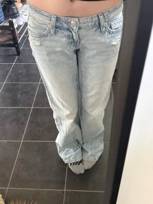 Ljusblå baggy jeans med slitningar - Säljer ett par ljusblå baggy jeans med låg midja. Användna 2 gånger. Har tyvärr ett litet hål nere i byxslutet. (kan skicka bild). skriv för frågor eller om pris!!