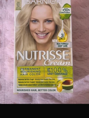 Garnier Nutrisse Cream hårfärg 101 - Permanent hårfärg från Garnier i nyansen 101 Extra Light Pearl Blonde. Innehåller tre oljor och en rik formula för djupvård. Ger upp till 100% täckning av grått hår och närande resultat. Förpackningen är vit och gul med detaljer i grönt.