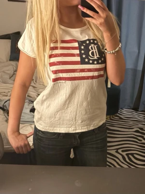 Vit t-shirt med amerikanskt flaggtryck - Vit t-shirt med korta ärmar och ett stort amerikanskt flaggtryck på bröstet💗