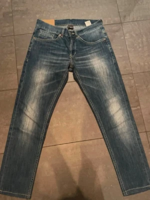 Ljusblå jeans från Dondup George  - Säljer ett par ljusblå jeans från Dondup med klassisk femficksmodell och kontrastsömmar. Jeansen har en rak passform och är tillverkade i mjukt denimtyg. Perfekta för en avslappnad och trendig look.