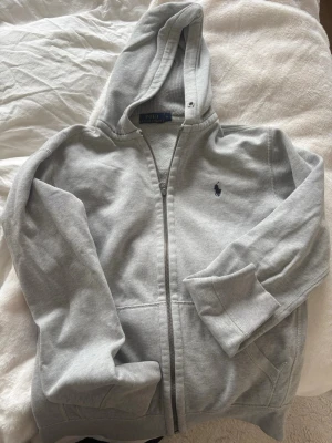 Grå hoodie från Polo Ralph Lauren - Säljer en grå Polo Ralph Lauren zip hoodie i bra skick.  Storlek: S   Färg: Grå   Skick: Bra skick    Obs: Snörena i huvan saknas, men påverkar inte användningen. Går att köpa billigt!  Snygg och stilren hoodie som passar till allt.  Nypris ca 1200–1500 kr.  Pris: 699 kr (kan diskuteras vid snabb affär)