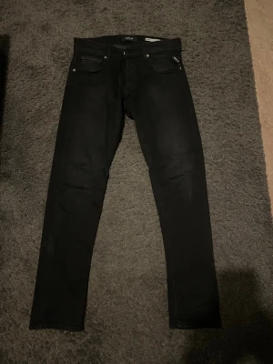 Svarta straight fit jeans från Replay - Säljer ett par svarta jeans från Replay med straight fit. Klassisk femficksmodell med Replay-logga vid fickan. Snygg och enkel design som passar till det mesta. Materialet är mjukt och stretchigt för extra komfort.