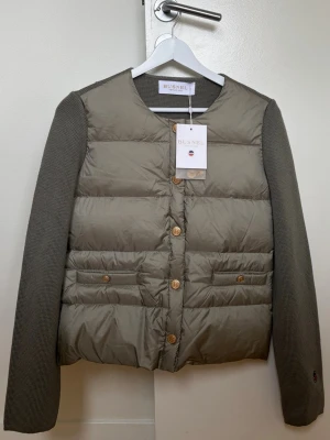 Busnel cardigan - Busnel jacka i modellen ”Iva Down Jacket”. Färgen är ljus olivgrön. Skulle säga att den är ljusare än på mina första bilder, sista bilden speglar färgen bättre. Helt ny med prislapp men dessvärre ett litet hål på höger axel, se bild 4. Går att laga. Nypris 4 595kr.