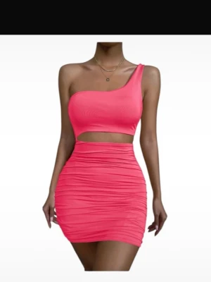 Rosa one shoulder kort klänning - Trendig rosa kortklänning med one shoulder-design och cut-out i midjan. Klänningen har en tight passform och är tillverkad i ett stretchigt syntetmaterial som framhäver figuren. Perfekt för dig som vill sticka ut med en färgstark och modern look.