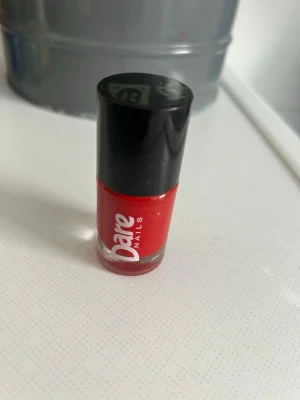 Rött nagellack Dare Nails - Snyggt rött nagellack från Dare Nails med klassisk glansig finish. Kommer i en liten rund glasflaska med svart lock. Perfekt för dig som vill ha starka, färgstarka naglar och gillar att sticka ut.