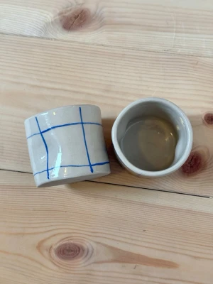 Handgjorda keramikmuggar med blått rutmönster - Espressomugg i keramik blå rutig – handgjord  Rymmer ca 100 ml.  Två stycken handgjorda espressomuggar i keramik. Perfekt för en god espresso eller som en fin detalj i köket.  Varje mugg är tillverkad för hand, vilket innebär att små variationer och naturliga ojämnheter kan förekomma – det är en del av hantverket och gör varje exemplar helt unikt.  Rekommenderas att handdiskas. Men tål diskmaskin och micro.  Handmade – fruitnclay 