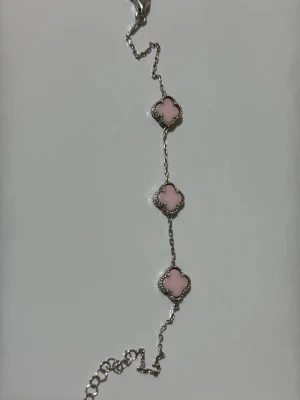 Silverarmband med rosa clover-detaljer - Snyggt armband i 925 silver med tre fyrklöverformade hängen i ljusrosa. Kedjan är tunn och smidig. Perfekt för dig som gillar söta och stilrena accessoarer. 
