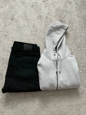 Paketerbjudande, ljusgrå zip hoodie med huva - Säljer en stilren ljusgrå hoodie med dragkedja och justerbar huva. Hoodien har en klassisk passform och är tillverkad i mjukt material, perfekt för en avslappnad look. Inga synliga loggor eller tryck, enkel och clean design.