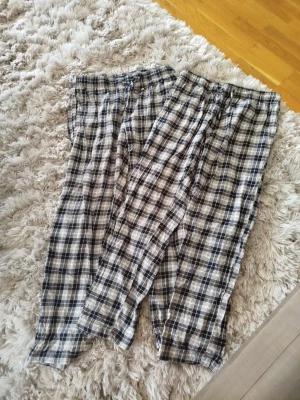 Rutiga pyjamasbyxor från 157 - Säljer två par rutiga pyjamasbyxor från 157 i svart, vitt och grått. Byxorna har resår i midjan och är gjorda i mjukt bomullstyg, perfekta för att chilla hemma. Klassisk rutig design som aldrig går ur tiden. Går att köpa en av dom om man vill ena paret är i storlek S och andra M 
