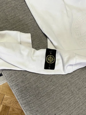 Vit hoodie från Stone Island - Stone island tröja vitt jätte fin och bra kvalietet xxl är slimfitt så det blir lite thight annars skulle jag rekommendera storlek L/M/XL skulle köpa.
