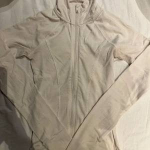 Zip up kofta från gina  - Säljer en kräm vit zip från Gina Tricot i storlek xxs. Jackan har en dragkedja framtill och långa ärmar. Perfekt för en stilren look. 