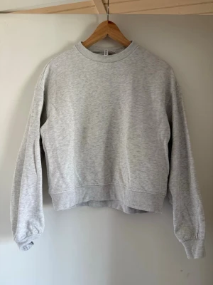 Ljusgrå basic sweatshirt - En enkel och stilren ljusgrå sweatshirt med rund halsringning och långa ärmar. Tröjan har ribbade muddar vid ärmslut och nederkant. Perfekt för en avslappnad och clean look. Materialet känns mjukt och bekvämt mot huden.