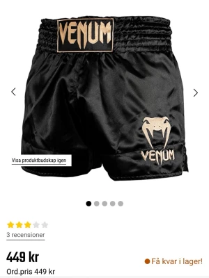 Svarta Muay Thai-shorts från Venum - Snygga svarta Muay Thai-shorts från Venum med guldig logga och ormmotiv framtill. Shortsen har bred resår i midjan och är tillverkade i glansigt, lätt material som ger bra rörelsefrihet. Perfekta för kampsportsträning eller sparring. Storleken är Large men skulle säga att den passar bättre för small eller medium.