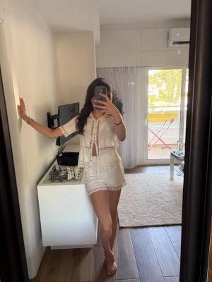 Vitt sett shorts och topp - Säljer ett superfint vitt set i spets med kortärmad topp och matchande shorts. Perfect för vacay
