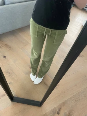 Juicy couture xs/s - Säljer ett par ljusgröna mjukisbyxor i mjukt velourmaterial. Byxorna har raka ben, bred resår i midjan och dragsko samt två fickor fram. Perfekta för chill dagar eller när du vill vara extra bekväm.
