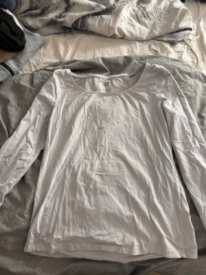 Vit långärmad basic topp - En enkel vit långärmad topp i mjukt bomullstyg. Modellen har rund halsringning och rak passform, perfekt att styla lager på lager eller bära som den är. Passar till det mesta och är ett måste i garderoben.