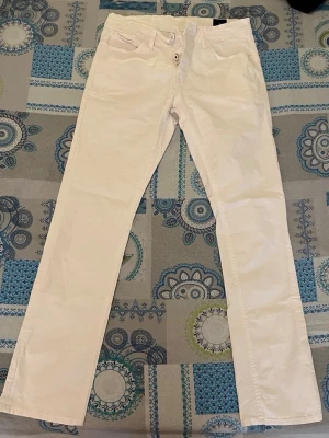 Vita chinos från Jack & Jones - Snygga vita chinos från Jack & Jones med klassisk rak passform och bälteshällor. Byxorna har framfickor och är tillverkade i bomull för en skön känsla. Perfekta för en stilren och fräsch look.