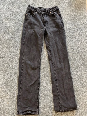 Svarta raka jeans - Snygga svarta jeans med rak passform och klassisk femficksdesign. Jeansen har normal midja och är tillverkade i ett slitstarkt denimtyg. Perfekta för en stilren och avslappnad look.