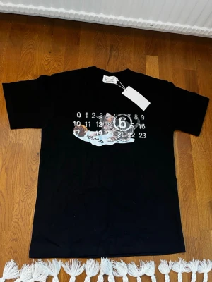 Maison Margiela T-Shirt Svart Katt, M - Säljer denna t-shirt i storlek M, men skulle säga att den är stor i storleken och passar perfekt även för en L! 