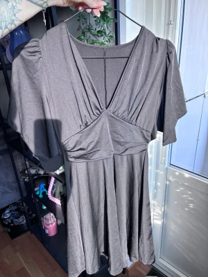 Svart sommarklänning - Snygg svart klänning med omlott-look och djup v-ringning. Klänningen har puffiga korta ärmar och ett mjukt, följsamt tyg som ger ett fint fall. Perfekt för dig som gillar en enkel men trendig stil. Otroligt skönt material och stretchig. Denna är aldrig använd utan råkade köpa två. 