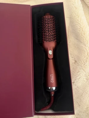 Big blowout heatbrush från Lyko - En vinröd elektrisk värmeborste från Lyko med rund form och svarta borstpiggar. Handtaget har en silverdetalj och borsten levereras i en matchande vinröd box. Perfekt för att styla håret smidigt och snabbt. Rekommenderar jättemycket!!  Den är lite ny, har använt en gång men jag har rengört den ordentligt! 