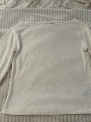 Vit långärmad topp från Nelly - Klassisk vit långärmad topp från Nelly i mjukt material. Enkel och stilren design med rund halsringning och rak passform. Perfekt att matcha med jeans eller kjol för en clean look.