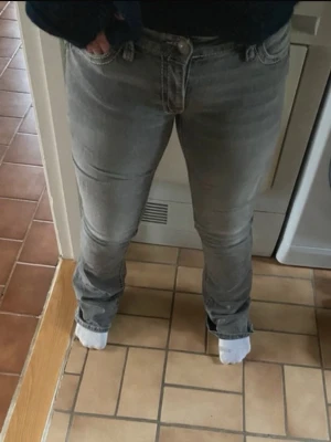 Gråa bootcut jeans med kontrastsömmar - Snygga gråa bootcut jeans med vita kontrastsömmar och klassiska fem fickor. Jeansen har normal midja. Passar perfekt till en avslappnad stil och är tillverkade i stretchigt denimtyg för extra komfort.