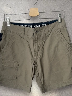 Beige cargo shorts från Sail Racing - Snygga beige cargo shorts från Sail Racing  med flera fickor, bland annat en praktisk ficka med lock på sidan. Klassisk passform med bälteshällor och knappstängning. Perfekta för sommardagar och chill häng.