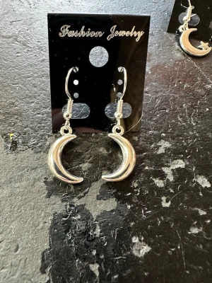 Silvriga crescent moon örhängen - Säljer ett par snygga örhängen i form av halvmånar i silverfärgad metall. De har en enkel krok och en clean, blank finish som ger en cool vibe. Perfekta för dig som gillar måndetaljer och vill sticka ut lite extra.