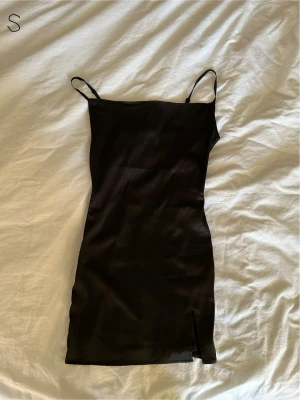 Svart satin klänning med slits - En svart, figurnära klänning i satin med tunna axelband och en liten slits framtill. Den är från SHEIN men köpte den begagnat och har endast testat den💗