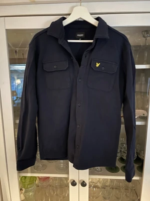 Mörkblå overshirt från Lyle & Scott - Säljer denna marinblåa overshirten från lyle & Scott junior. Storlek 15-16 years men passar xs. Hör av dig vid intresse eller minsta fråga.