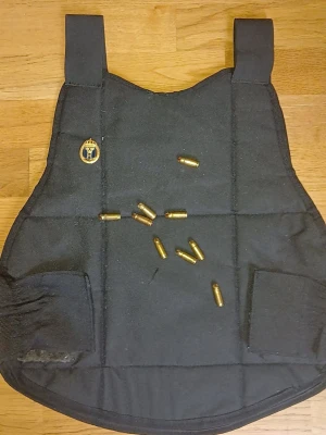 Svart skyddsväst med hemvärnets emblem - Svart skyddsväst med broderat emblem på vänster sida. Västen har breda axelband och elastiska sidopaneler för bättre passform. Materialet är slitstarkt tyg och designen är enkel och funktionell. Obs: patronerna ingår ej.