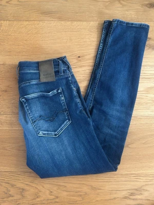 Blå jeans från Replay  - Snygga blå jeans från Replay, modell Grover. Jeansen har klassisk femficksdesign, smal passform och coola slitningar. Märkesdetaljer på fickorna och bak vid linningen. Perfekta för en trendig och avslappnad look. Sitter som 30/32 ish! Stretch passform. Mvh