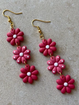 Handgjorda statementörhängen i rosa – blomdesign - Handgjorda statementörhängen i polymerlera  Varje blomma är formad för hand vilket gör att varje par är unikt och kan variera något i detaljer.  Ca 8 cm långa – tydliga men fortfarande lätta att bära.  Antiallergiska detaljer Lätta trots storleken Guldfärgade detaljer Flera par finns  Skriv om du vill se exakt par innan köp  Skickas