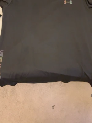 Svart märkes tshirt  - Svart märkes tshirt från under armour. Har prislapp, den har regnbågig reflective märken. Perfekt för sommaren